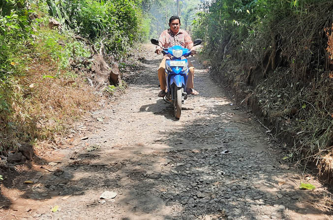 AKAN DIASPAL: Bendahara Desa Sepoh Gembol Mulyadi melintas di jalan desa Dusun Saksak yang akan diaspal ulang, tahun ini. (Foto: Fahrizal Firmani/Jawa Pos Radar Bromo)