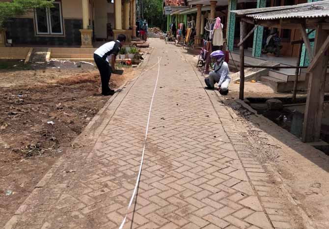 AWALNYA TANAH PADAT: Petugas melakukan pengukuran pada paving di RT 13 RW 5 di Dusun Beringin yang sudah rampung tahun ini. (Fahrizal Firmani/Jawa Pos Radar Bromo)