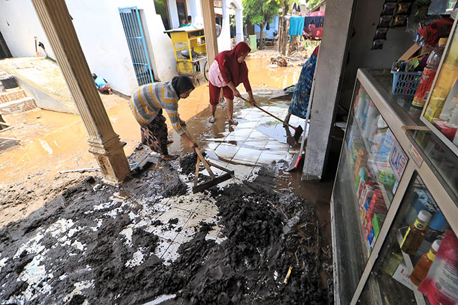 BERSIH-BERSIH: Beberapa warga Dusun Suko, Desa Sukorejo, Kecamatan Pohjentrek membersihkan rumah mereka setelah banjir bandang terjadi. (Mokhamad Zubaidillah/Radar Bromo)