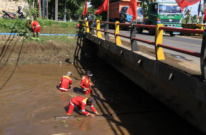 PADAHAL SERING DIBERSIHKAN: Petugas Dinas PUPR membersihkan Kali Petung. Meski sudah dinormalisasi, Sungai Petung masih kerap meluap saat hujan deras. (Foto: Dok. Radar Bromo)