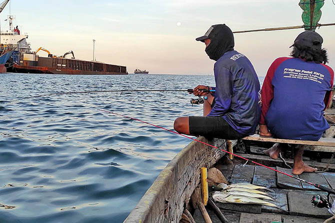 MENGAIL IKAN: Beni dan Budi memancing di perairan laut Probolinggo. Selain menyalurkan hobi, mereka juga ngabuburit. (Ainul Mashudi/Radar Bromo)