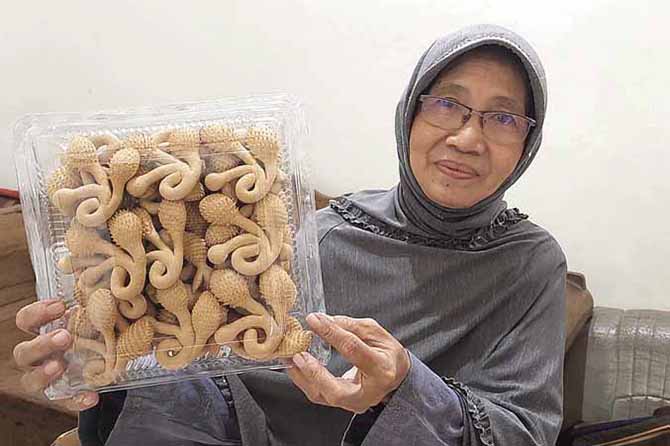 PRODUKSI: Faridha Ruhmi, menunjukkan kue banjar yang sudah dikemas dan siap dipasarkan. Serta, sejumlah kerabatnya terlihat telaten memproduksi kue banjar. (Foto: Rizky Putra Dinasti/Jawa Pos Radar Bromo)