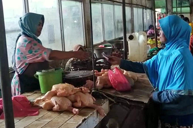 TRANSAKSI: Salah seorang pedagang daging ayam di Pasar Kebonagung, Kota Pasuruan, melayani pembeli, kemarin (9/4). (Mukhamad Rosyidi/Radar Bromo)