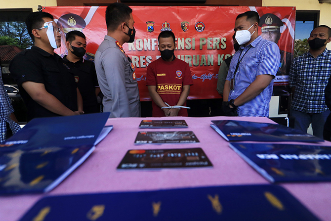 AKHIRNYA MENYERAH: Syaiful Efendi dan sejumlah barang bukti penipuan modus Trading Crypto saat kasusnya dirilis di Mapolres Pasuruan Kota, kemarin. (Mokhamad Zubaidillah/Radar Bromo)