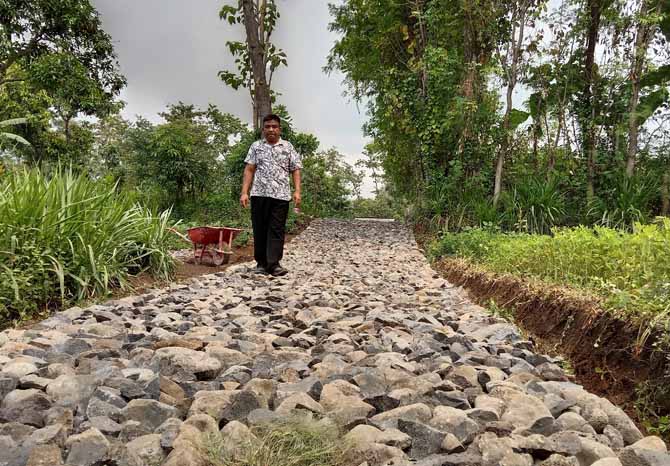 LEBIH BAIK: Kasi Pembangunan Desa Purut Sutiarso mengecek hasil pembangunan jalan makadam di RT 6/RW 2 Dusun Genjeng. (Foto: Achmad Arianto/Radar Bromo)