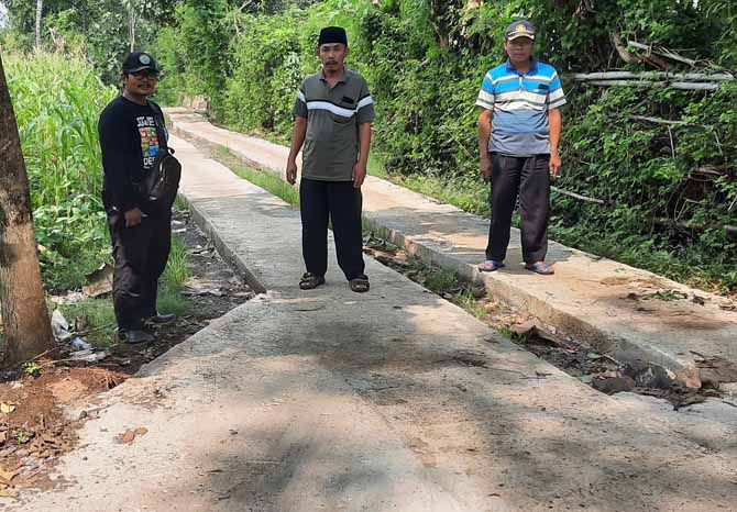 LEBIH BAIK: Kepala Desa Gunung Tugel Asen (pakai kopiah) menunjukkan jalan yang telah dirabat beton di Dusun Uter, Desa Gunung Tugel. (Foto: Fahrizal Firmani/Jawa Pos Radar Bromo)