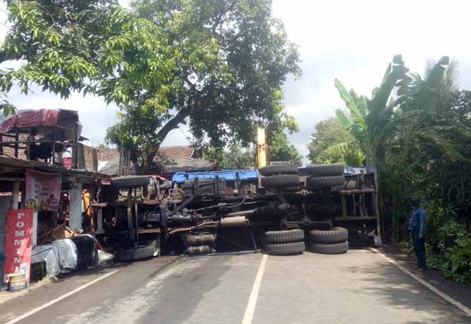 TERGULING: Dump truck yang alami rem blong terguling usai menabrak sejumlah bangunan dan kendaraan di Jalan raya pasrepan, Rabu (18/5). (Foto: M Rosyidi/Jawa Pos Radar Bromo)