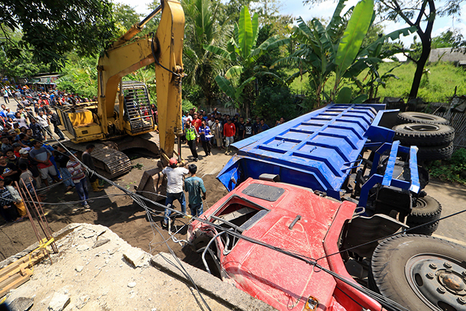 LUMPUHKAN AKSES: Petugas mengerahkan alat berat untuk mengevakuasi truk muat sirtu yang terguling malang melintang di jalur Bromo via Pasuruan, Rabu (18/5). (Mokhammad Zubaidillah/ Radar Bromo)