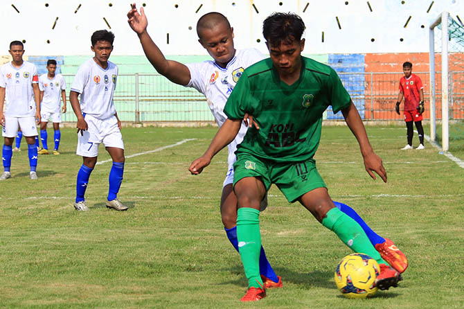 CETAK ANGKA: Tegar Ilhamsyah (hijau) dikawal pemain tim Kabupaten Bondowoso dalam laga Pra Porprov di stadion Untung Suropati Selasa (10/5) siang. (Foto: M Zubaidillah/Jawa Pos Radar Bromo)