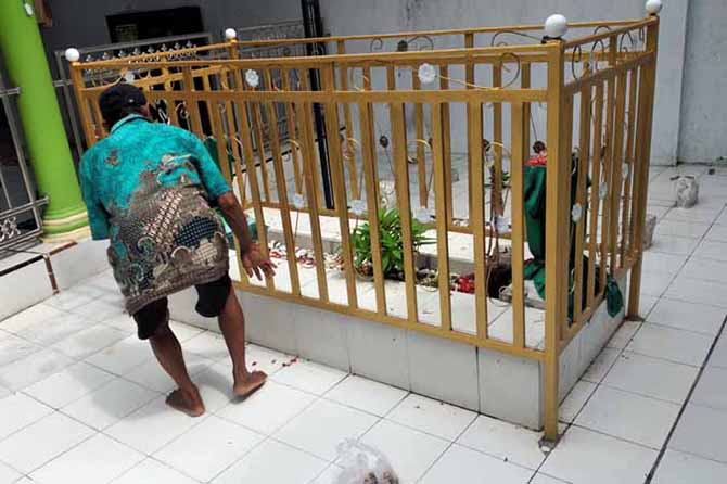 DIBERSIHKAN: Husen, salah satu anak turunan Mbah Rancang yang juga juru kunci sedang membersihkan makam Mbah Rancang di Desa Lemah Kembar, Kecamatan Sumberasih, Kabupaten Probolinggo. (Foto: Fuad Alyzen/Jawa Pos Radar Bromo)