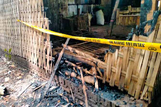 DISELIDIKI: Garis polisi yang dipasang di sekitar kandang di rumah Sn. Kandang ini sempat dibakar massa, Kamis (2/6) malam. (Foto: Agus Faiz Musleh/Jawa Pos Radar Bromo)