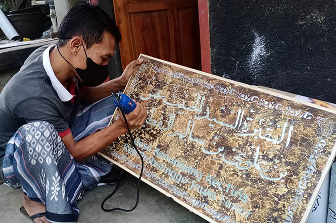 KREATIF: Andika membuat kaligrafi berbahan pipa paralon yang didatarkan. Karyanya yang unik membuat banyak orang tertarik untuk memiliki. (Achmad Arianto/Jawa Pos Radar Bromo)