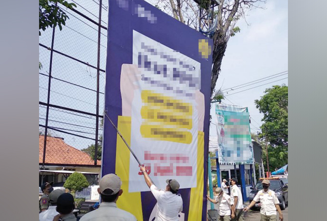 DICOPOT: Satpol PP Kota Pasuruan saat mencopot salah satu reklame besar milik instansi pemerintahan. Reklame itu dibawa ke Mako Satpol PP.