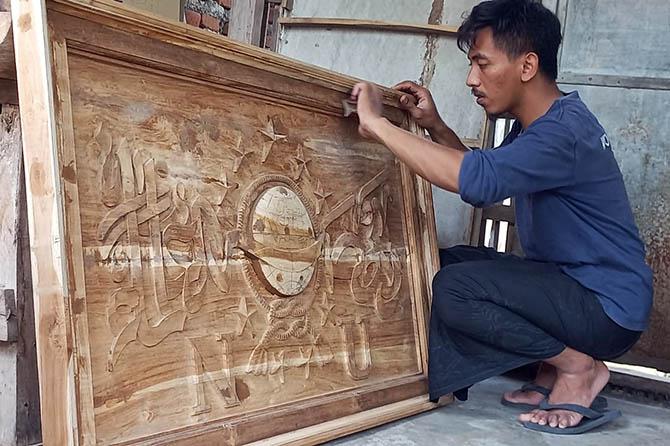 SENI: Arif Budiono saat menggarap pesanan ukiran kaligrafi di tempatnya bekerja. (Mukhamad Rosyidi/Radar Bromo)