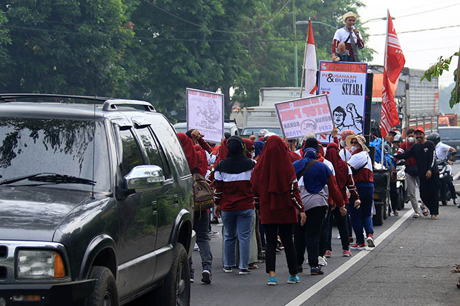 UNJUK RASA: Para buruh ATI saat menggelar aksi unjuk rasa dengan jalan mundur di Bundaran Apollo Gempol hingga depan pabrik ATI, Gempol. (Mokhamad Zubaidillah/Jawa Pos Radar Bromo)
