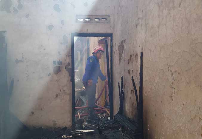 PEMBASAHAN: Personel damkar melakukan pembasahan di rumah Sugiarto yang terbakar Kamis (28/7) pagi. (Foto: Istimewa)