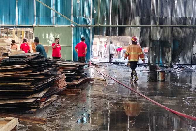 AMUK SI JAGO MERAH: Petugas saat berupaya memadamkan api yang berkobar di pabrik pengolahan kayu PT Sakari.