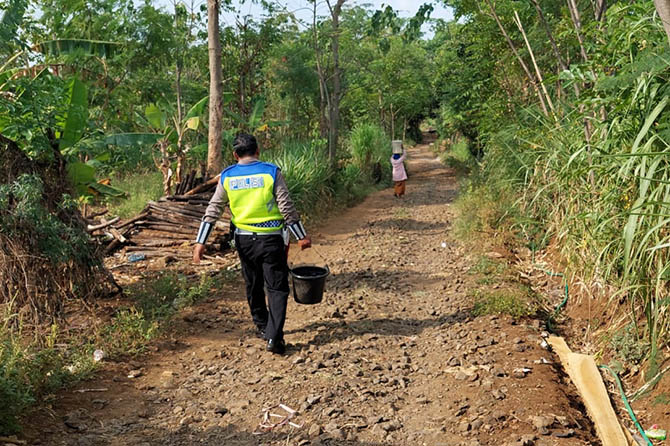 Sejumlah warga RT 8/RW 3, Dusun Krandon, Desa Tandonsentul, Lumbang, membawa ember berisi air bersih. (Rizky Putra Dinasti/Jawa Pos Radar Bromo)