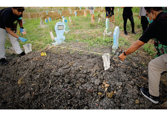 Petugas Polres Lamongan melakukan olah TKP di lokasi makam yang dicuri tali pocongnya. (Jawa Pos Radar Bojonegoro)