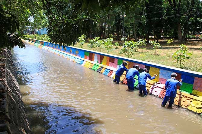 LEBIH CANTIK: Sejumlah pekerja mengecat plengsengan sungai dengan cat warna-warni. (Mokhamad Zubaidillah/Radar Bromo)