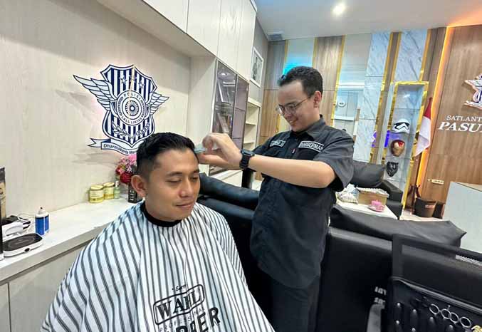 TERMPIL: Achmad Sholeh saat mencukur rambut Kasatlantas Polres Pasuruan, AKP Yudhi Anugrah Putra. (Foto: Iwan Andrik/Jawa Pos Radar Bromo)