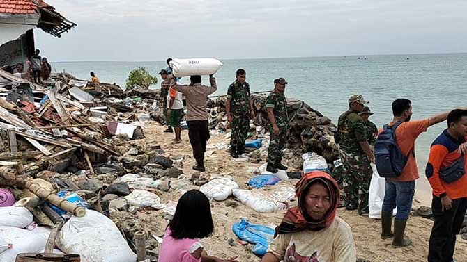 BANTU WARGA: Petugas saat membawa material untuk tanggul sementara di Gili Ketapang.