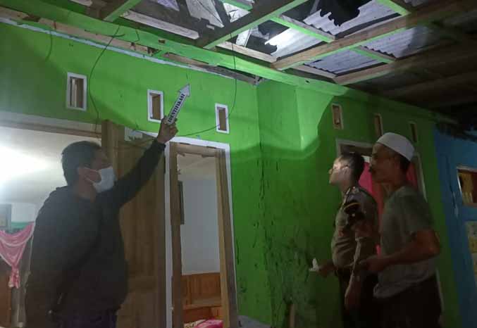 SAMPAI JEBOL: Personel kepolisian menunjukkan atap di rumah Neto usai dilempar bondet pada Minggu (27/11) lalu. (Foto : dok Jawa Pos Radar Bromo)