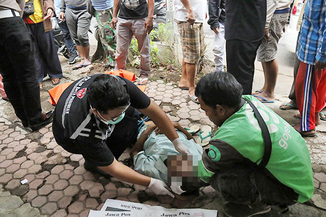 MENINGGAL DI JALAN: Warga mengevakuasi jasad Robi yang meninggal saat mengantarkan penumpang becak di Jalan dr Wahidin Sudiro Husodo. (Mokhamad Zubadillah/Radar Bromo)