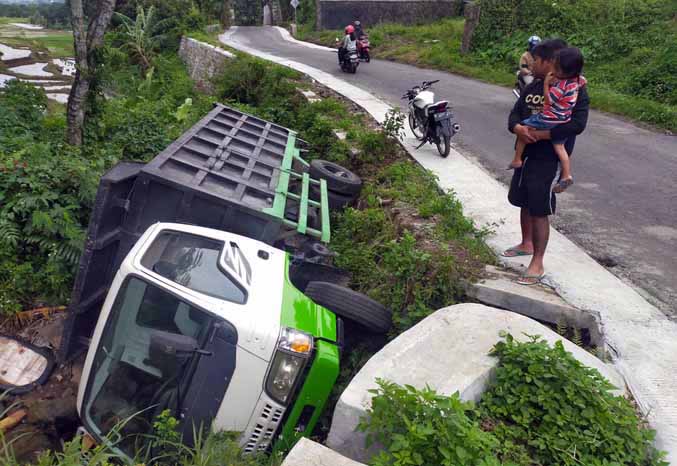 JADI TONTONAN: Warga melihat truk muatan aspal nyemplung ke parit di Dusun Kasin, Desa Sukoreno, Kecamatan Prigen. (Foto: Rizal F. Syatori/Jawa Pos Radar Bromo)