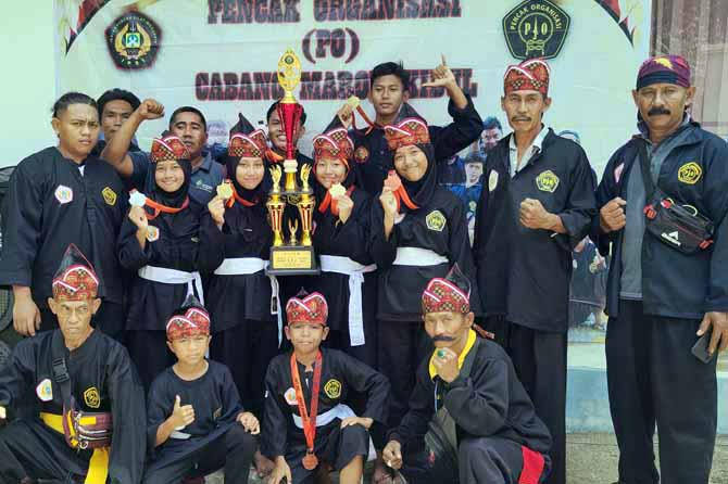 MEMBANGGAKAN: Pesilat Pencak Organisasi Cabang Maron Kidul dengan pelatih dan pendamping memarkan trofi kejuaraan pencak silat Jember National Championship 1. (Foto: Achmad Arianto/Jawa Pos Radar Bromo)