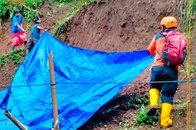 ANTISIPASI: Tim reaksi cepat BPBD Kabupaten Probolinggo bersama warga memasang terpal pada sisa tebing longsor di Desa Andungbiru, Kecamatan Tiris. (Foto: Dok. Radar Bromo)