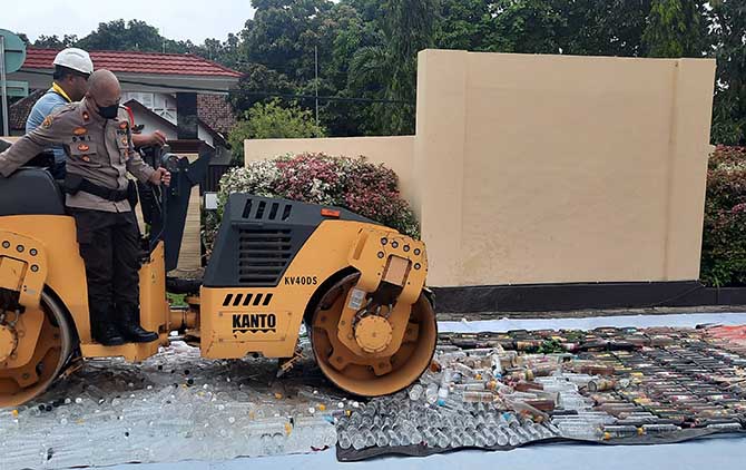 DIMUSNAHKAN: Ribuan botol miras hasil razia Polres Probolinggo Kota dimusnahkan menggunakan alat berat Jumat, 31 Desember 2022. (Fahrizal Firmani/Jawa Pos Radar Bromo)