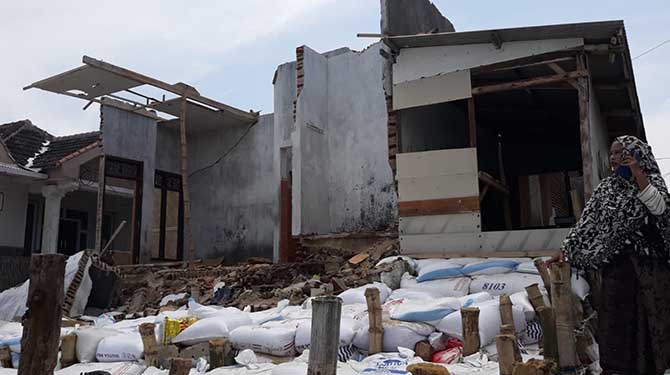 TAK BERBENTUK: Seorang warga melihat sejumlah rumah di Desa Gili Ketapang, Kecamatan Sumberasih, Kabupaten Probolinggo, yang rusak diterjang gelombang. (Fahrizal Firmani/Jawa Pos Radar Bromo)