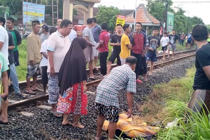 NAHAS: Warga saat hendak mengevakuasi jenazah korban yang tewas tertabrak KA komuter di jalan terobosan.