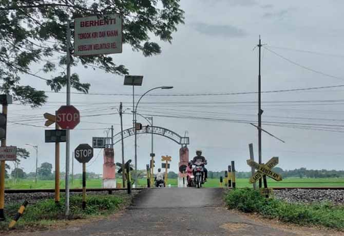 LOKASI KEJADIAN: Pengendara motor melintas di jalur pantura di depan perlintasan KA di Dusun Kasuruan, Desa Rejoso Lor, lokasi keluarga Pasutri Said-Mina disasak KA. (Foto: Fuad Alyzen Jawa Pos Radar Bromo)