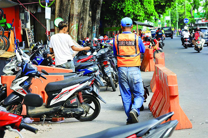 BERTUGAS: Seorang jukir bertugas di Jalan Panglima Sudirman Kota Probolinggo, beberapa waktu lalu. Sudah tiga tahun honor jukir tak naik, tetap Rp 700 ribu per bulan. (Dok. Radar Bromo)