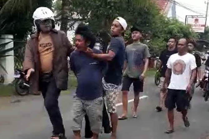 JADI SASARAN AMUK: Saneman (tengah) dikeler petugas usai dibekuk di Krejengan, Rabu (25/1) siang. (Foto: Screenshot)