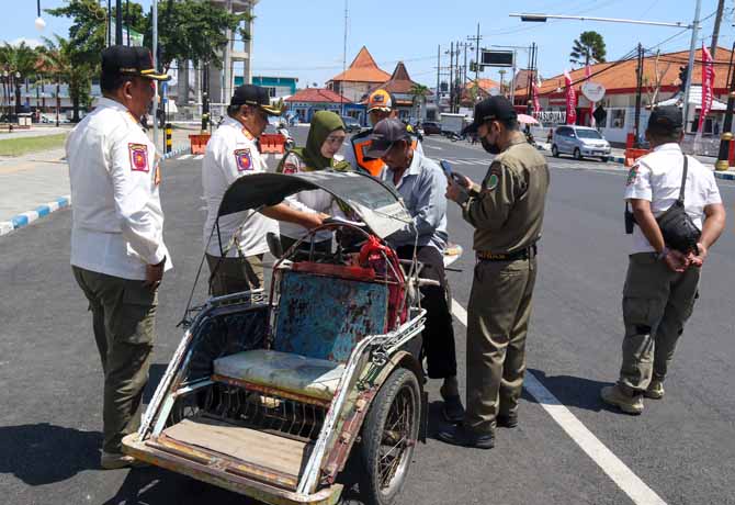 STOP: Sejumlah anggota Satpol PP dan Dishub Kota Pasuruan menghentikan pengendara becak motor. Mereka diminta tidak memasuki jalan perkotaan, terutama di kawasan alun-alun. (Foto: Mokhamad Zubaidillah/Jawa Pos Radar Bromo)