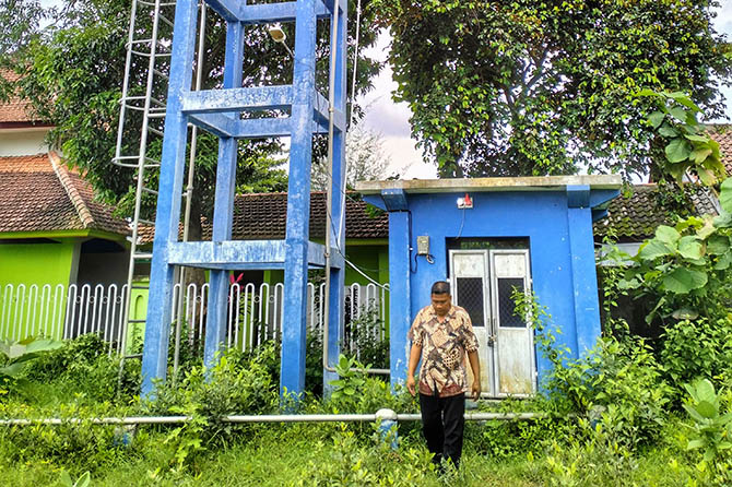 PENUHI KEBUTUHAN: Kasi Pembangunan Desa Banjarsawah Nasin mengecek kondisi tandon dan pompa air. Pemenuhan kebutuhan air bersih dilakukan oleh pemerintah desa setempat. (Achmad Arianto/Jawa Pos Radar Bromo)
