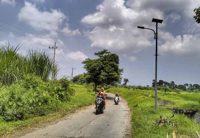 AKAN DITAMBAH: Beberapa warga sedang melintas di jalan Dusun Grintingan yang sudah terpasang PJU panel tenaga surya. Tahun ini PJU akan dipasang di Dusun Jurangan. (Foto: Achmad Arianto/Jawa Pos Radar Bromo)