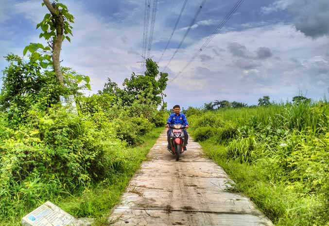 MULUS: Sekretaris Desa Sumberbulu Muhammad Aminullah melintasi jalan rabat beton di RT 7/RW 1, Dusun Krajan yang rampung dibangun tahun lalu. (Foto: Achmad Arianto/Jawa Pos Radar Bromo)
