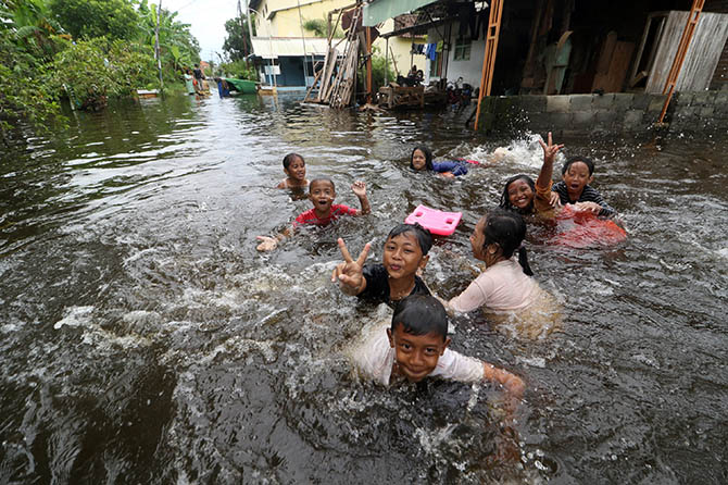 SEKOLAH LIBUR: Sejumlah anak-anak sedang bermain genangan banjir di Desa Rejoso Lor, Kecamatan Rejoso, Kabupaten Pasuruan, Senin (13/2) siang. Akibat banjir yang melanda, sekolah setempat terpaksa mengganti proses belajar mengajar tatap muka dengan sistem