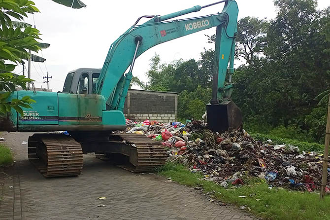 PAKAI ALAT BERAT: Sebuah alat berat dikerahkan untuk mengangkat sampah yang 2 tahun dibuang di eks lahan Puskesmas Gempol. (Rizal Syatori/Radar Bromo)