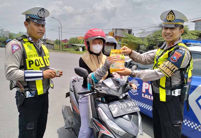 POLISI BAIK: Anggota Satlantas Polres Pasuruan memberikan hadiah untuk pengendara Jumat (10/2). (Foto: Rizal F. Syatori/Radar Bromo)