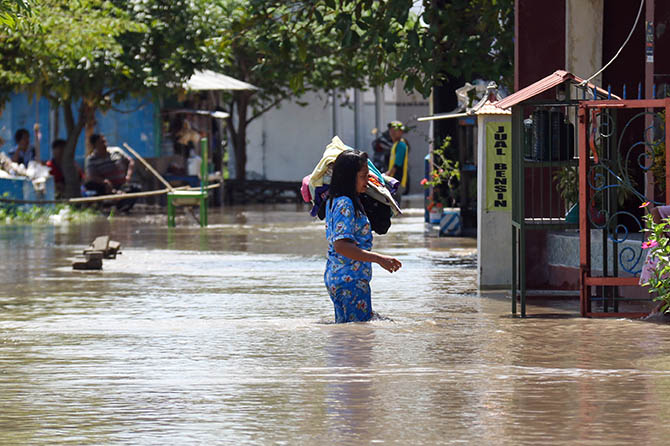 Jalanan di Desa Masangan terendam banjir hingga lebih dari selutut orang dewasa. Nampak salah satu warga membawa barang berharga melewati banjir. (Mokhamad Zubaidillah/Radar Bromo)
