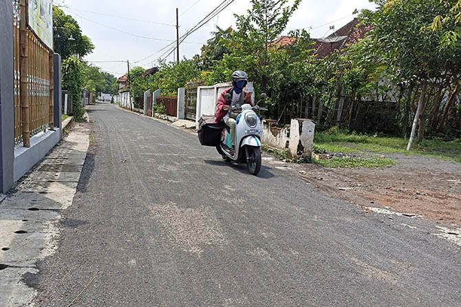 KIAN NYAMAN: Seorang pengendara melintas di jalan desa di Dusun Sedempok, Desa Rondokuning, yang rampung diaspal lapen Maret ini. (Istimewa)