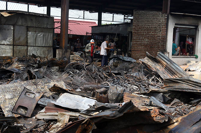 BERSIH-BERSIH: Pedagang Pasar Karangketug yang lapaknya terbakar, mengambil sisa barang setelah garis polisi dilepas per Selasa (28/2). (M Zubaidillah/Jawa Pos Radar Bromo)