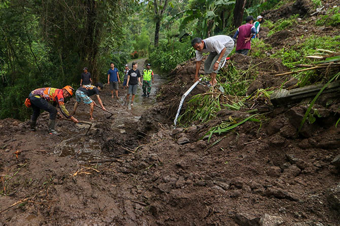 BERSIH-BERSIH: Warga Tretes, Kecamatan Prigen dibantu sejumlah instansi membersihkan jalanan dari material banjir bandang. (Mokhamad Zubaidillah/Radar Bromo)