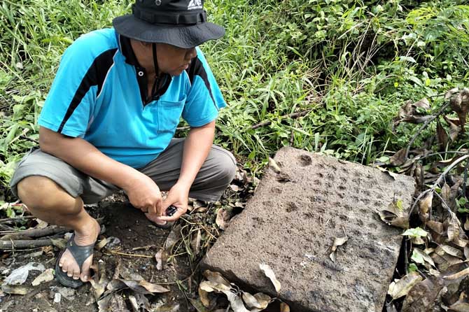 Warga menunjukkan salah satu benda diduga cagar budaya dekat makam di Dusun Tebas, Desa Kepulungan, Gempol. (Rizal Syatori/ Radar Bromo)