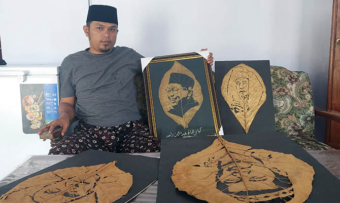 HARUS TELATEN: Rijalullah menunjukkan sejumlah hasil karyanya berupa kaligrafi dan gambar ulama yang menggunakan “kanvas” daun pohon jati. (Rizky Putra Dinasti/Jawa Pos Radar Bromo)